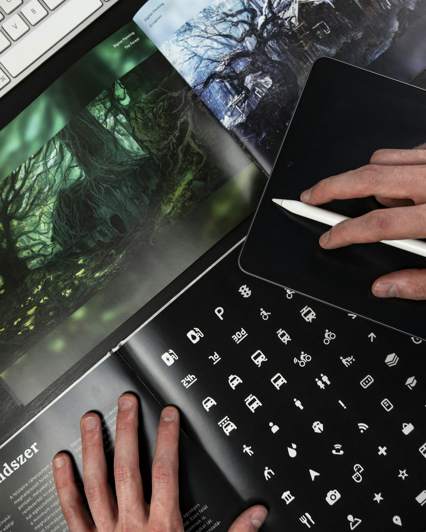 Designer illustrating on a tablet beside printed design work